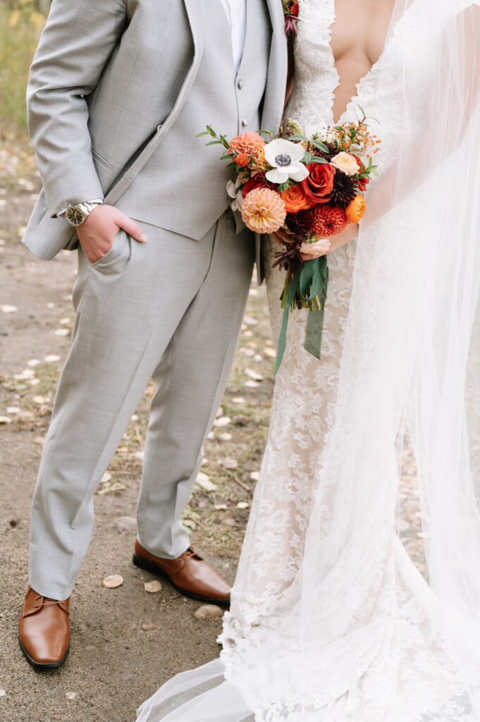 Close-up of bridal bouquet with dahlias, roses, and anemones in warm fall tones.
Colorado mountain wedding ceremony with rust-colored floral installation.