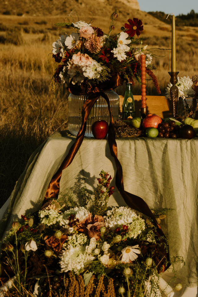 Western ranch wedding table-scape with seasonal florals, fruit, and candles at golden hour