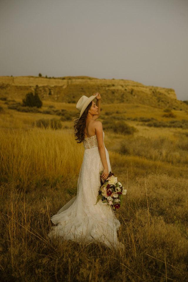 Romantic ranch wedding portrait with bride holding bouquet in tall grass