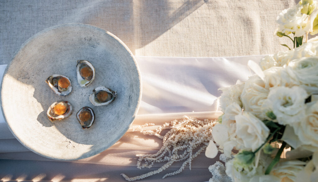 Coastal table styling with oysters, neutral linens, and organic florals