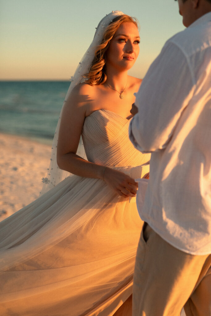 Bride and groom exchanging vows during intimate Emerald Coast vow renewal
Emotional moment between couple beneath sheer veil at golden hour