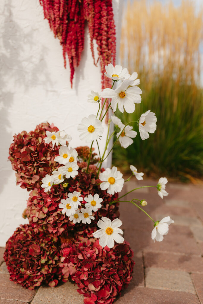 Outdoor wedding ceremony setup at The Manor House Colorado with white floral columns and Denver skyline in the distance