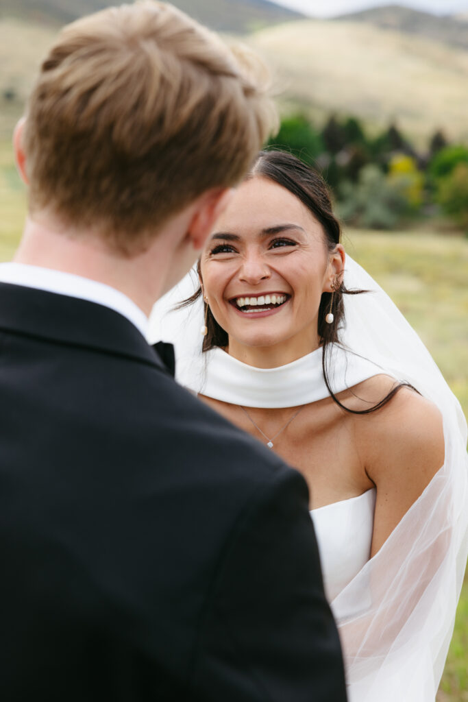 Bride laughing joyfully at groom during first look at Manor House Colorado wedding