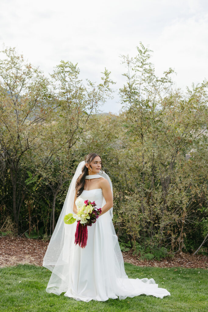 Full-length bridal portrait at The Manor House Littleton Colorado — bride in strapless gown holding burgundy and green bouquet