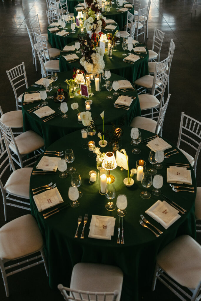 Elegant wedding reception at The Manor House Colorado with emerald green tablecloths, candlelight, and white floral centerpieces