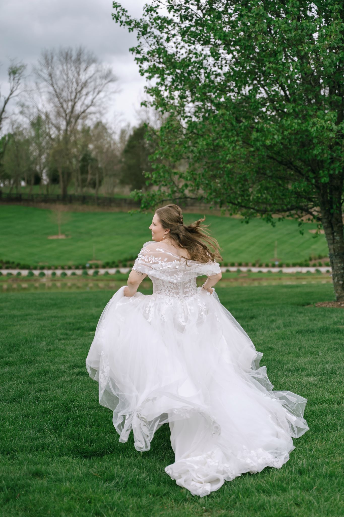 Bride twirling her lace gown on the lawn