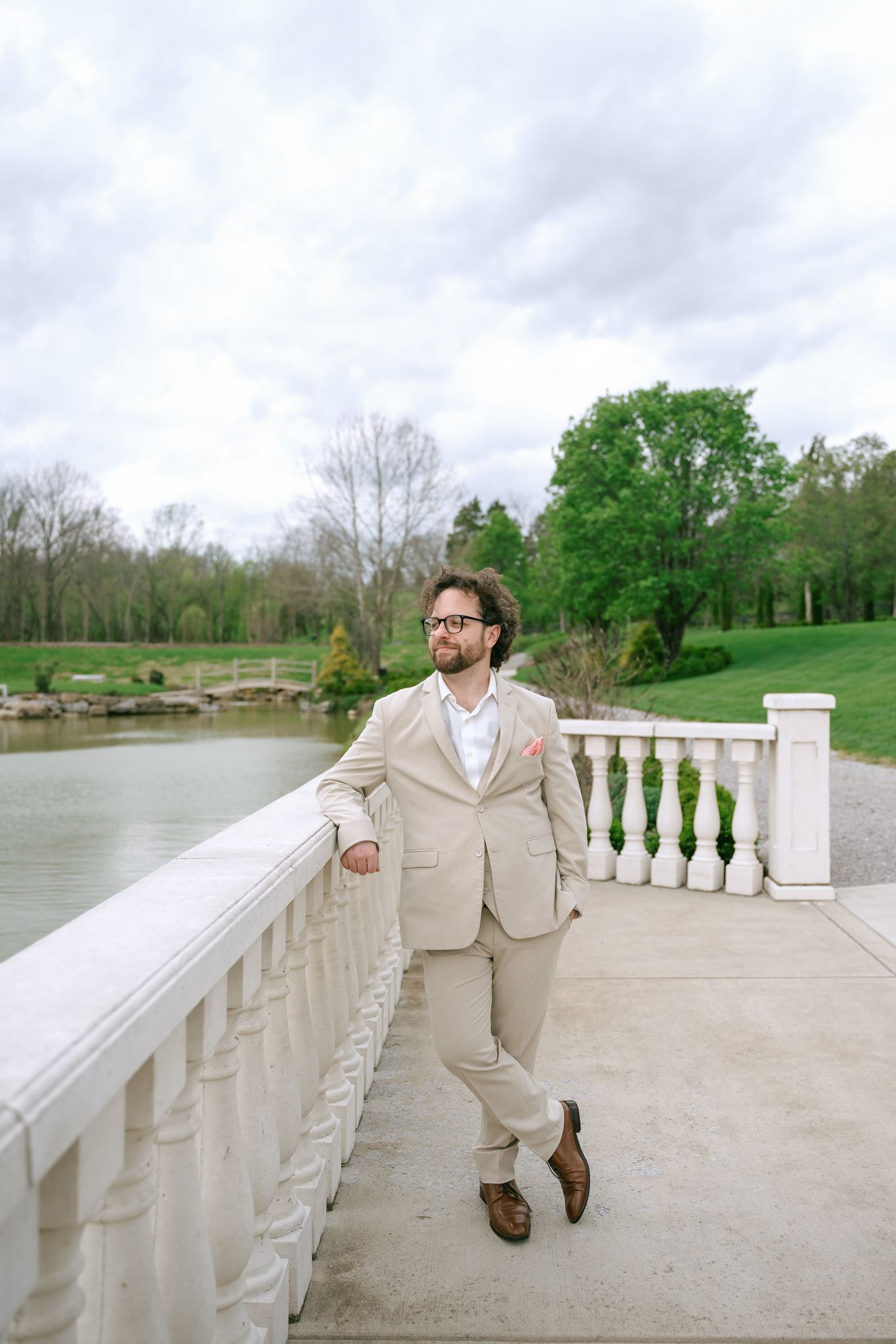 Groom in a tan suit beside the pond at Hazelnut Farm