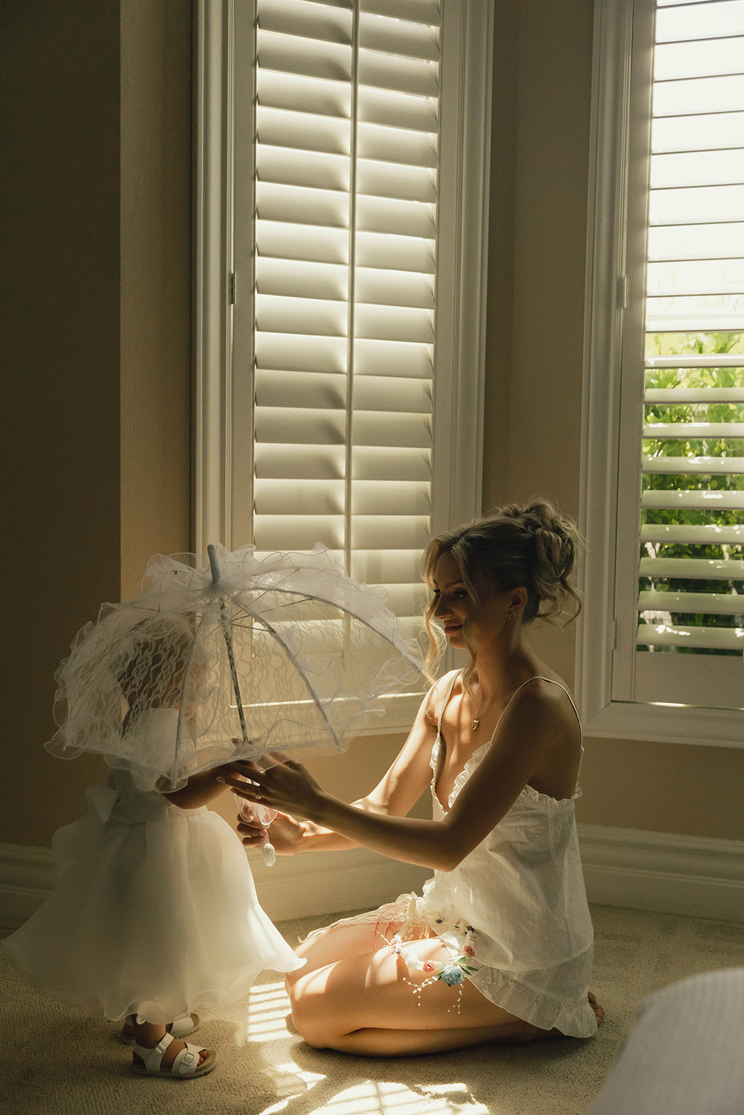 Bride with a lace umbrella by the window while getting ready