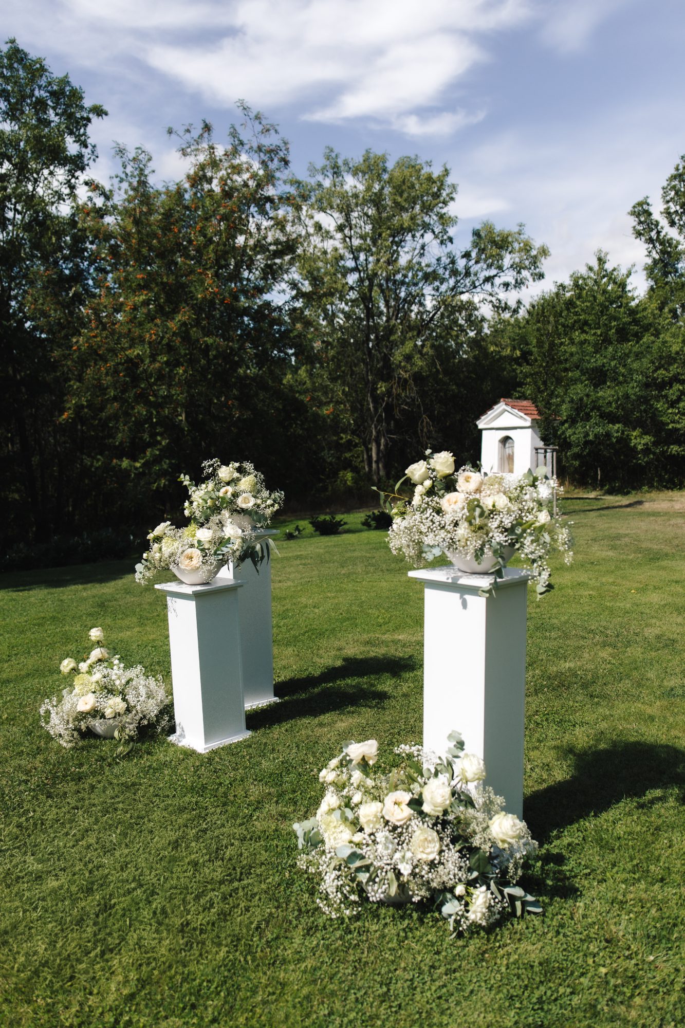 Outdoor wedding ceremony pillars with white florals on the lawn at Samota Pierre